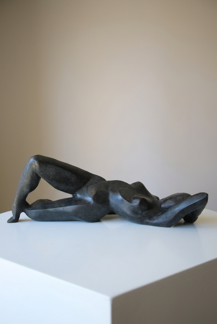 Femme à facettes d’Anne-Gaëlle Arnaud, femme allongée en bronze sur un socle blanc, présentée en format vertical