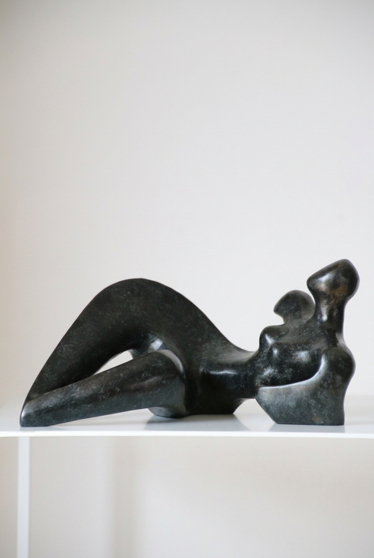 Figure de style d’Anne-Gaëlle Arnaud, femme allongée stylisée en bronze sur fond clair, présentée en format vertical