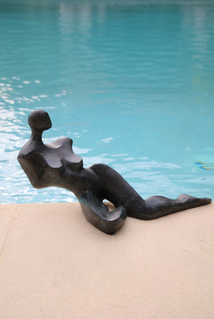 Figure étendue stylisée d’Anne-Gaëlle Arnaud, sculpture en bronze au bord d’une piscine, présentée en format vertical