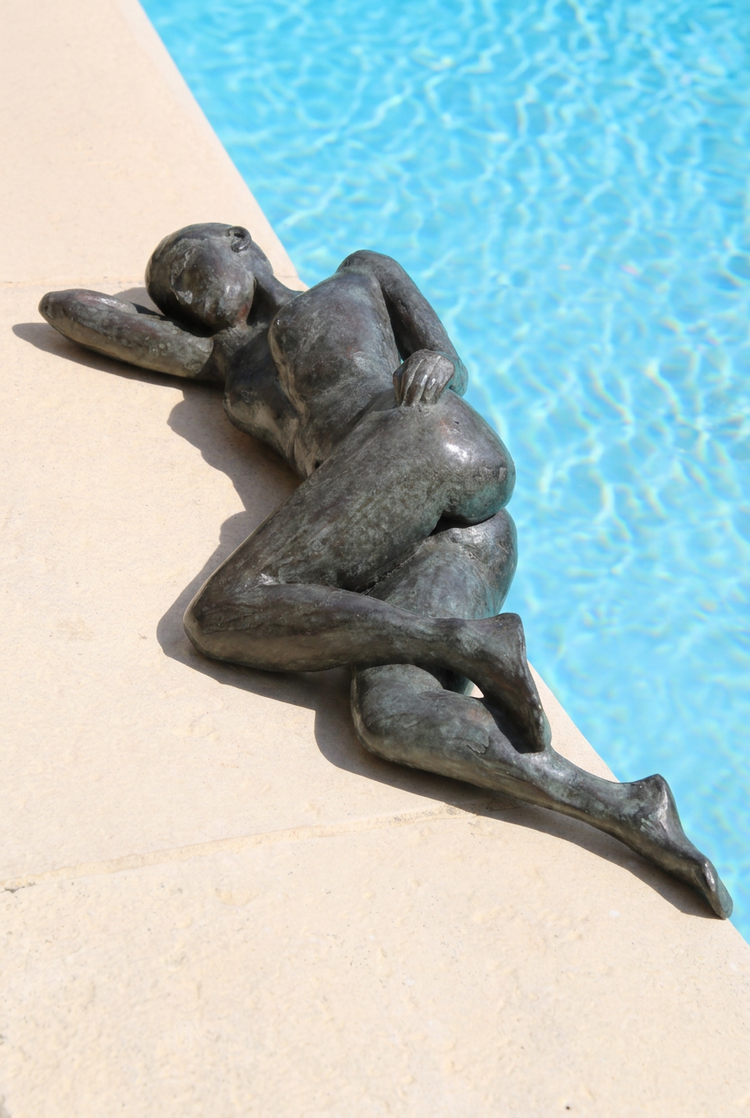 Jeune femme alanguie d’Anne-Gaëlle Arnaud, femme allongée en bronze au bord d’une piscine, présentée en format vertical